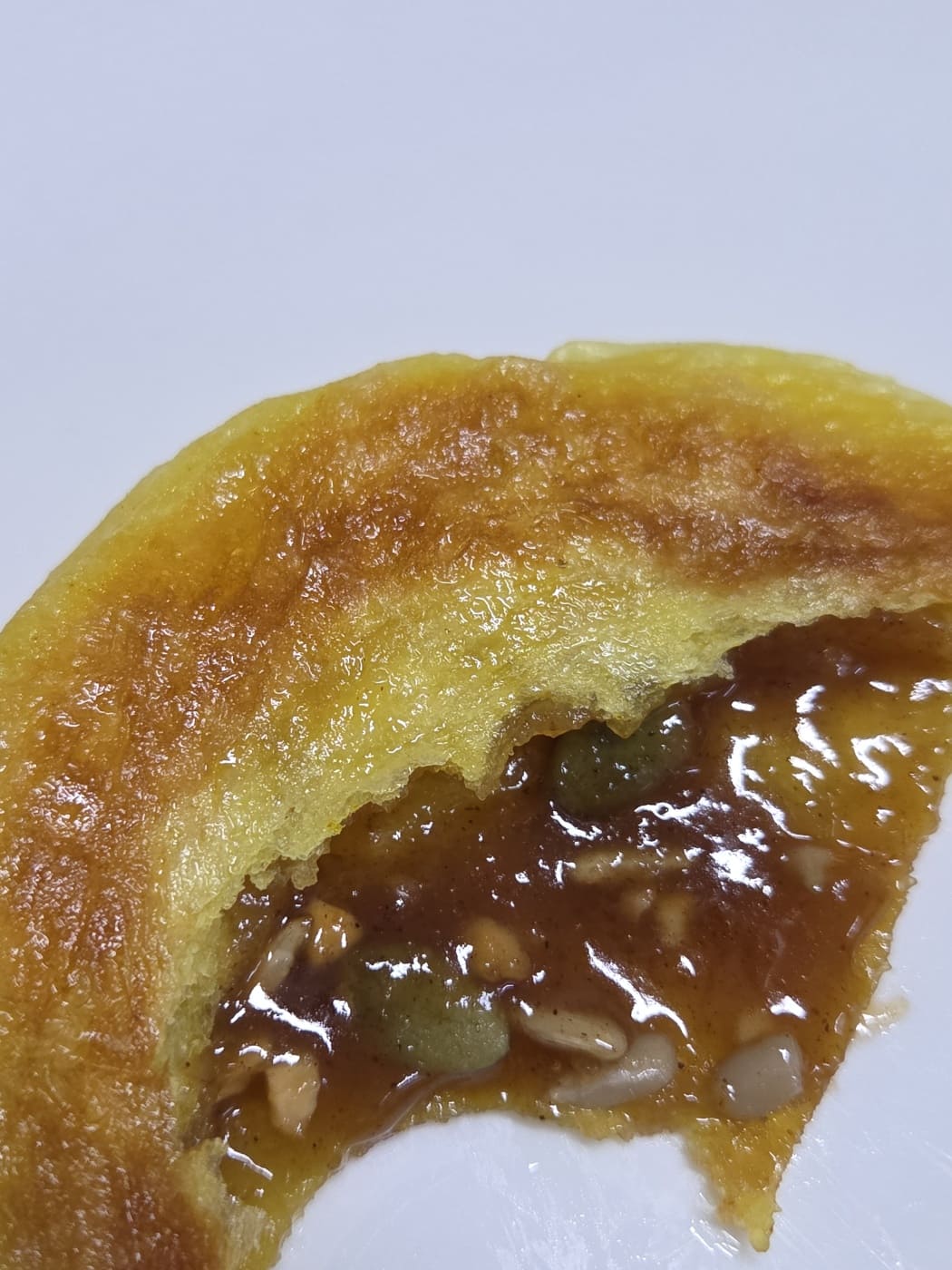 Close-up of Ssal Yeon-Ip hotteok cross-section with molten brown sugar syrup and nuts flowing out.